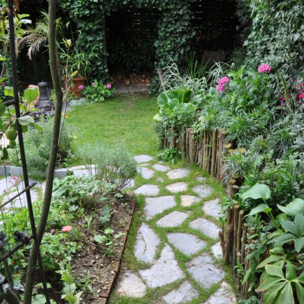 Im Garten lockere Steinplatten mit Gras dazwischen. Kleansis Plakes Steinplatten.