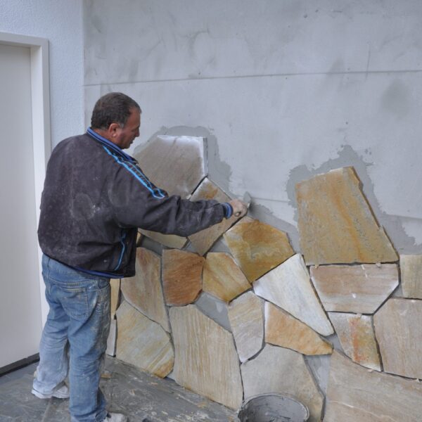 Maurer - Mauerwerke Polygonalplatten an die Wand im Inneren.